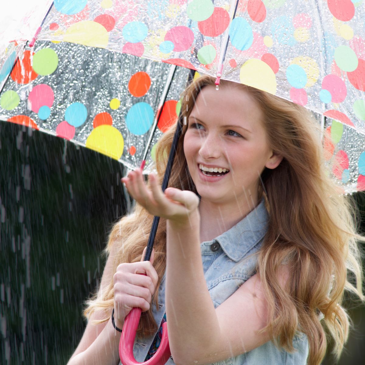 woman in rain with brightly coloured polka dot umbrella