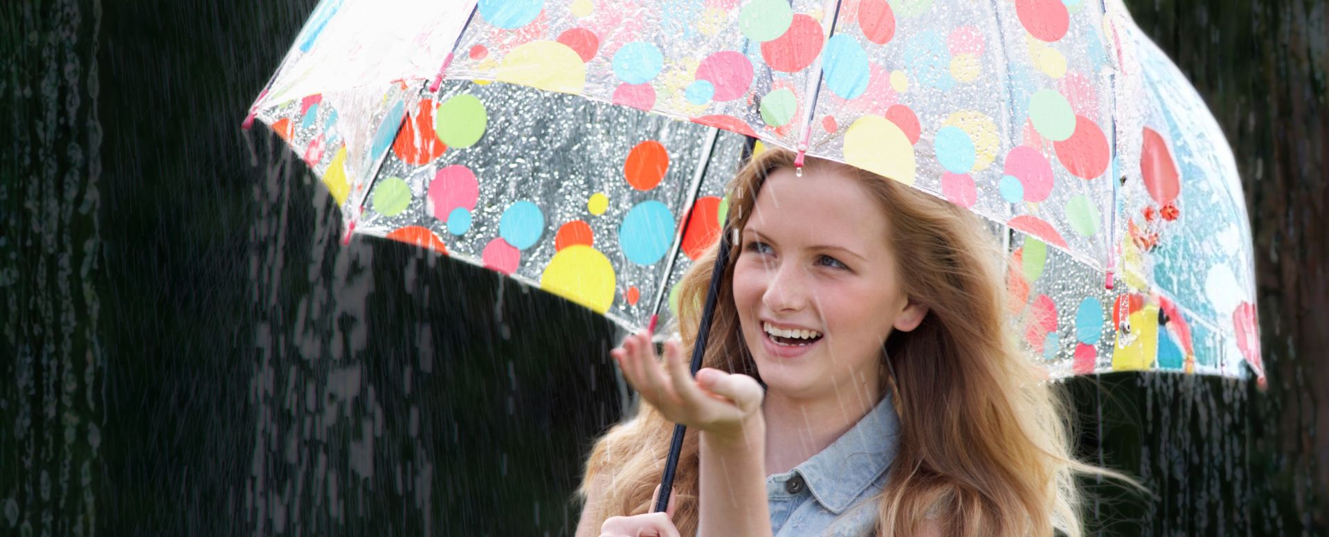 woman in rain with brightly coloured polka dot umbrella